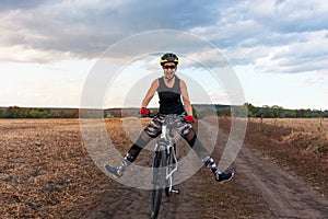 Joyful girl rides a bicycle on a field road