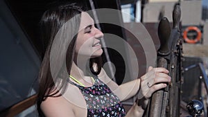 Joyful girl rotates the ship`s steering wheel