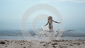 Joyful girl running swim in beautiful sea summer day. Woman splashing in ocean.