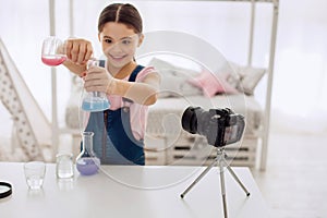 Joyful girl showing how colors change in chemical flasks