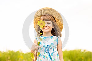 Joyful girl smiling and covering face with sunflower in field
