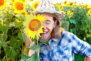 Joyful girl with sunflowers and closed eyes showing tongue