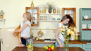 Joyful girls dancing and shaking long hair in the kitchen