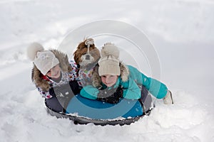 Joyful girls ride a tubing from a hill together. Winter holiday