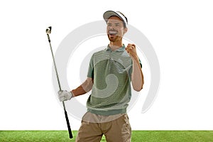 Joyful golfer in retro outfit and cap celebrating perfect goal with raised fist and golf club stands on green court