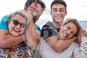 Joyful group of mothers and sons, several generations of the same family, have fun outdoors by the sea. From teenager to grandma