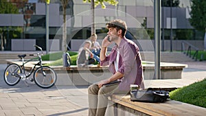 Joyful guy answering call in urban park closeup. Cheerful freelancer speaking