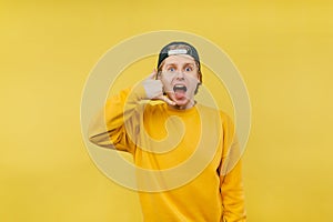 Joyful guy in a cap and casual clothes shows a ring gesture with his fingers and looks at the camera with an emotional face