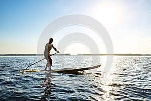 Joyful guy paddling on a SUP board