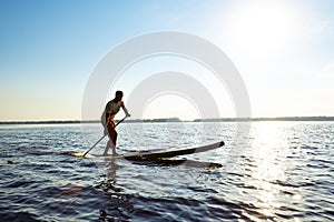 Joyful guy paddling on a SUP board