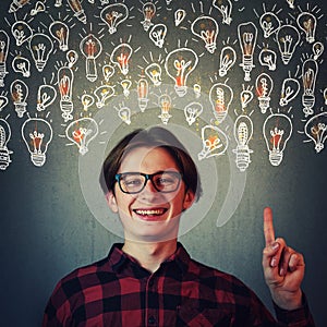 Joyful guy pointing index finger up, showing multiple light bulbs as creative ideas isolated on grey wall background. Positive