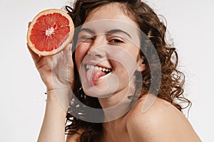 Joyful half-naked girl with grapefruit winking and showing her tongue