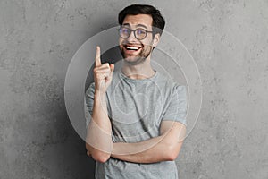 Joyful handsome guy smiling and pointing finger upward