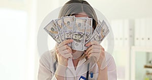Joyful happy doctor holding money in the clinic