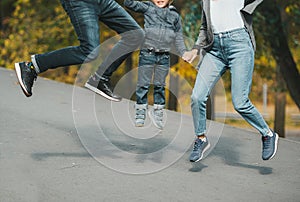 Joyful happy family jump on country road in autumn. Closeup