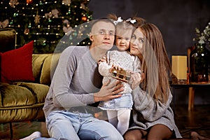 Joyful happy family with little baby girl in aesthetic cozy home interior near festive Christmas tree. Beautiful couple