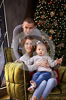Joyful happy family with little baby girl in aesthetic cozy home interior near festive Christmas tree. Beautiful couple
