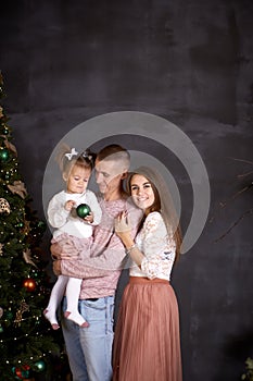 Joyful happy family with little baby girl in aesthetic cozy home interior near festive Christmas tree. Beautiful couple