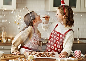 Joyful happy family mother and girl daughter having fun while baking christmas cookies in kitchen