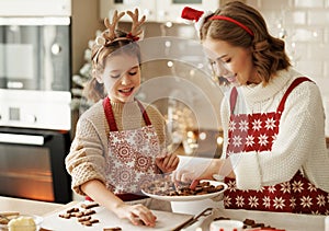 Joyful happy family mother and girl daughter having fun while baking christmas cookies in kitchen