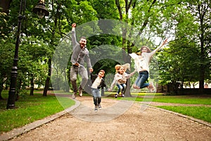 Joyful happy family in summer park together jumping have fun