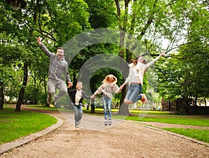 Joyful happy family in summer park together jumping have fun