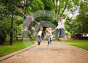 Joyful happy family in summer park together jumping have fun