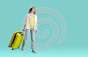 Joyful happy young female tourist or vacationer with suitcase goes on summer trip.