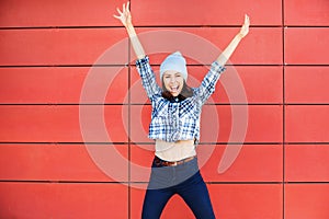 Joyful happy young woman jumping against red wall. Excited beautiful girl portrait