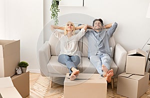 Joyful Husband And Wife Relaxing On Couch In New Home