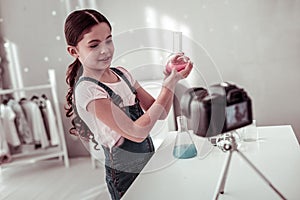 Joyful intelligent girl holding a small flask