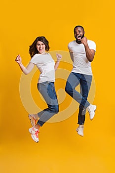 Joyful interracial couple jumping in air and shouting with excitement