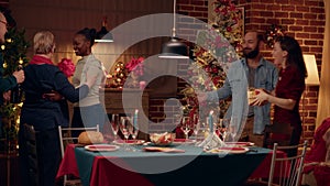 Joyful interracial couple welcoming guests to Christmas dinner at home