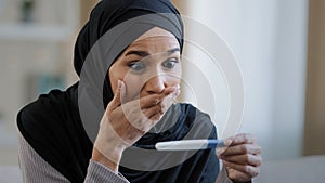 Joyful islamic young woman in hijab smiling happily holding pregnancy test excited pregnant lady surprised and happy