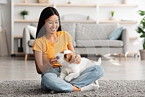 Joyful japanese lady giving her doggy treats at home