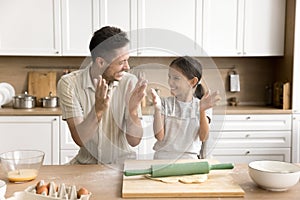 Joyful kid girl and happy dad having fun while baking