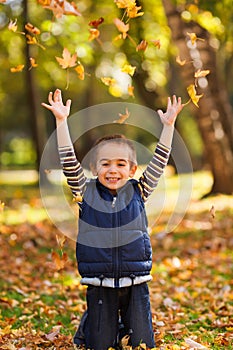 Joyful kid playing with leaves