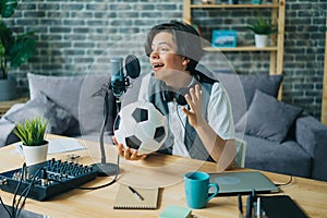 Joyful kid recording audio about football holding ball talking in microphone