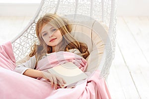 Joyful kid relaxing in bedroom with literature