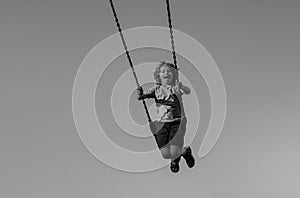 Joyful kid swinging on a swing. Happiness children. Child extreme swinging. Danger high Swing in sky. Craziness and photo