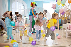 Joyful kids and clown play with color balloon on birthday party