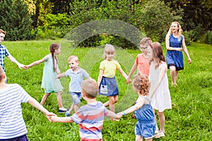 Joyful kids dancing holding hands in summer park.