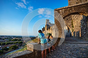 Joyful kids explore Carcassonne castle at sunset, enjoy panorama