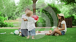 Joyful kids playing with balls in park. Three kids having fun in summer park
