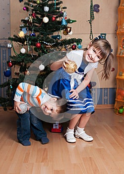 Joyful kids playing in a Christmas tree (3 years and 6 years)