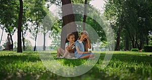 Joyful kids playing under tree. Smiling children have fun outdoors on weekend.