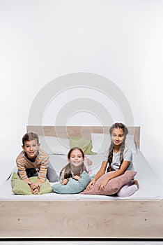 joyful kids sitting on bed with