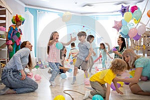 Joyful kids and their parents entertain and have fun with color balloon on birthday party