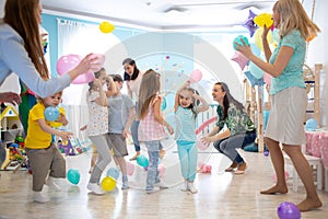 Joyful kids and their parents entertain and have fun with color balloon on birthday party