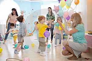 Joyful kids and their parents entertain and have fun with color balloon on birthday party